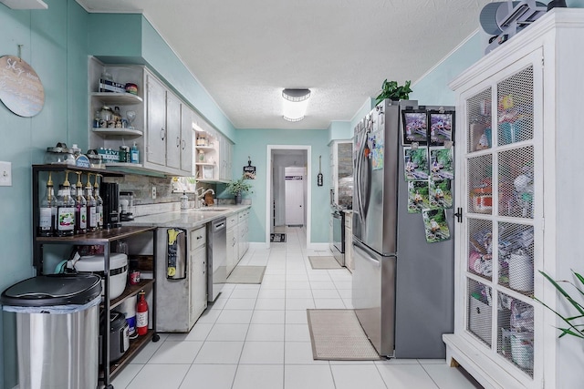 kitchen with appliances with stainless steel finishes, tasteful backsplash, a textured ceiling, sink, and light tile patterned flooring