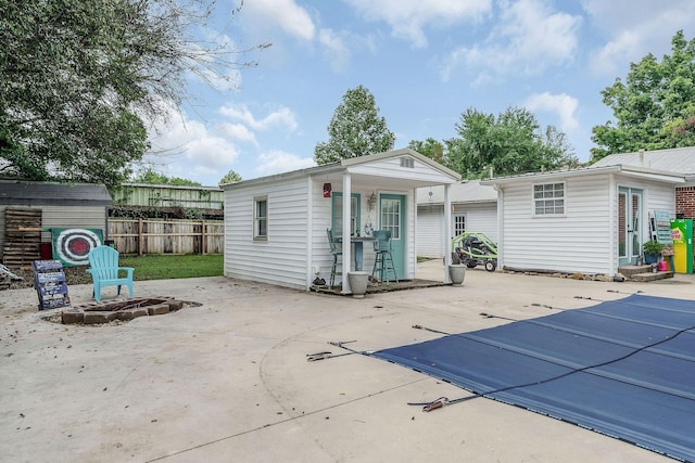 back of house featuring a patio, a fire pit, a covered pool, and an outdoor structure