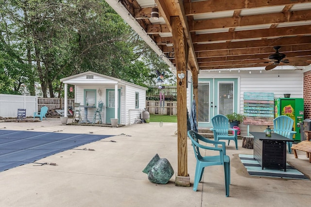 view of patio with an outbuilding, a covered pool, and ceiling fan