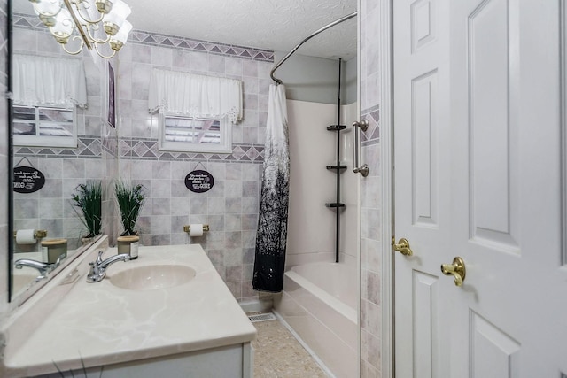 bathroom featuring vanity, shower / bathtub combination with curtain, a textured ceiling, and an inviting chandelier