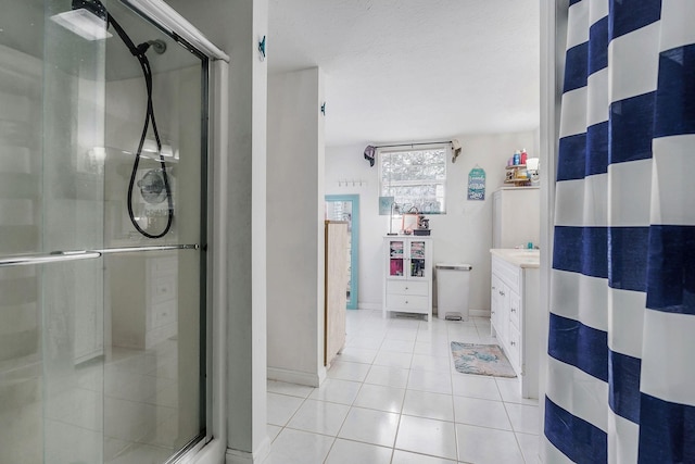 bathroom featuring tile patterned flooring, vanity, a textured ceiling, and walk in shower