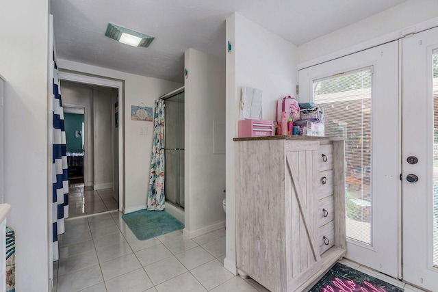 bathroom with toilet, tile patterned flooring, a textured ceiling, and walk in shower