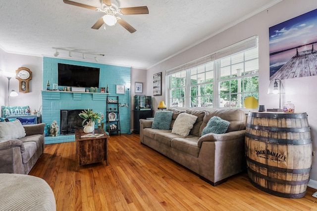 living room with a brick fireplace, ornamental molding, a textured ceiling, and hardwood / wood-style flooring