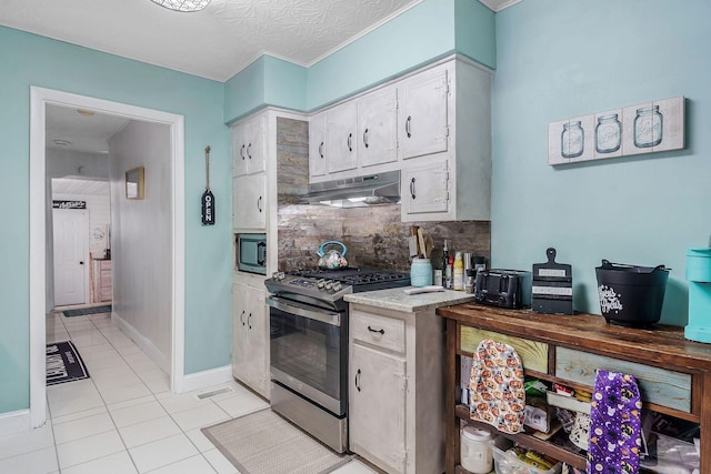 kitchen with appliances with stainless steel finishes, a textured ceiling, tasteful backsplash, and light tile patterned flooring