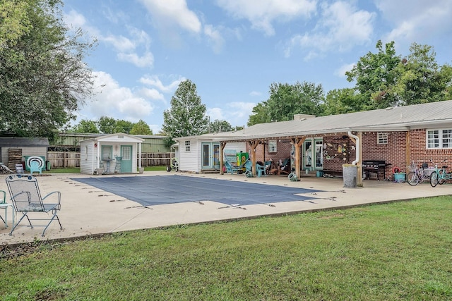 view of swimming pool with a lawn, a storage unit, area for grilling, and a patio