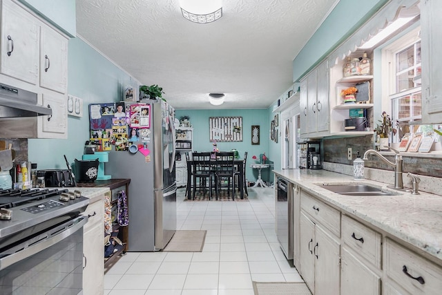 kitchen featuring appliances with stainless steel finishes, a textured ceiling, light tile patterned floors, and sink