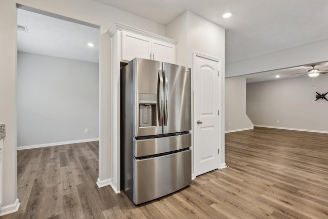 kitchen with stainless steel fridge, white cabinets, light hardwood / wood-style floors, and ceiling fan