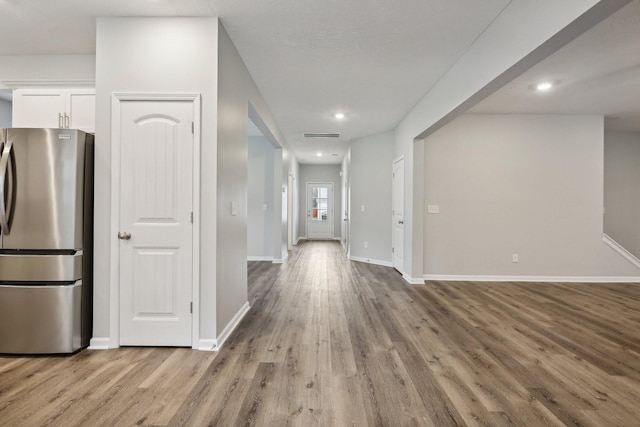 kitchen featuring white cabinets, stainless steel fridge, and light hardwood / wood-style floors