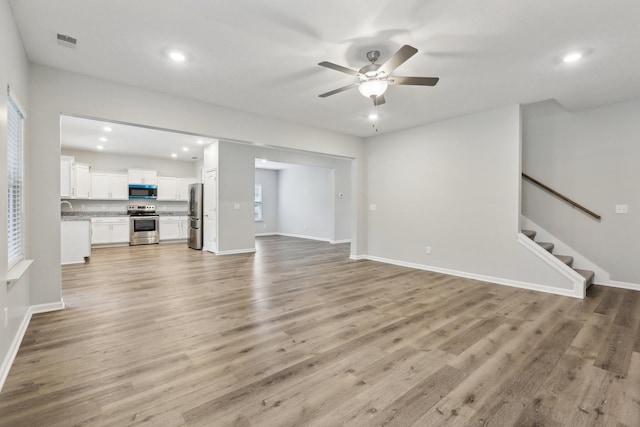 unfurnished living room featuring ceiling fan and light hardwood / wood-style floors