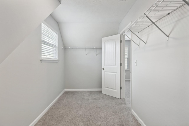 spacious closet with light colored carpet and vaulted ceiling