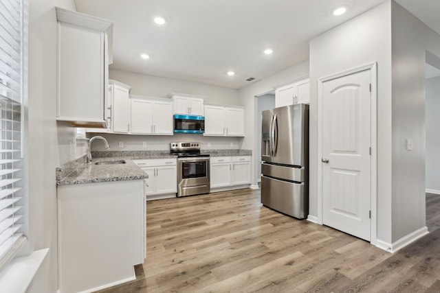 kitchen with white cabinetry, sink, stainless steel appliances, and light stone counters