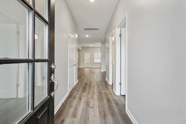 hallway with a textured ceiling and light wood-type flooring