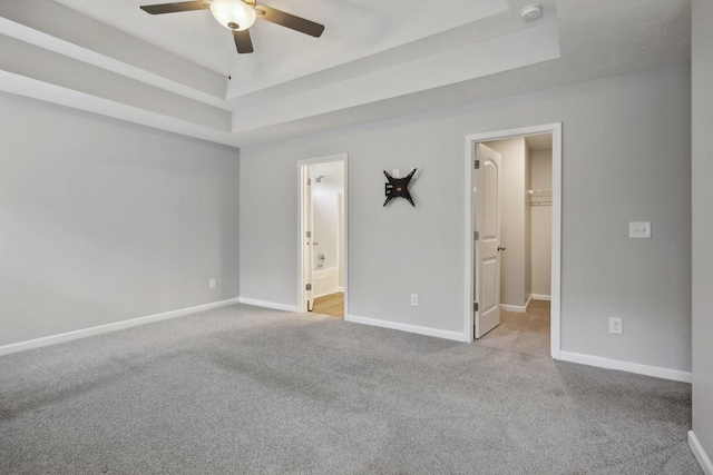 spare room with a tray ceiling, ceiling fan, and light colored carpet