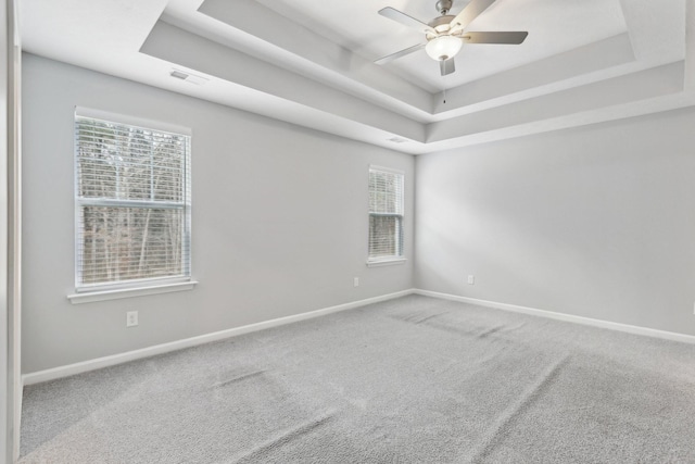 unfurnished room featuring a tray ceiling, ceiling fan, and carpet floors