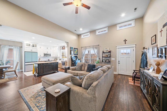 living room with ceiling fan, dark hardwood / wood-style flooring, and a high ceiling