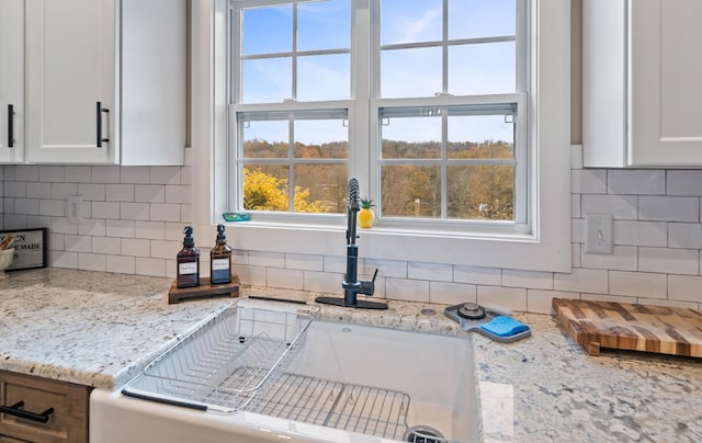 kitchen featuring light stone countertops, tasteful backsplash, and white cabinetry