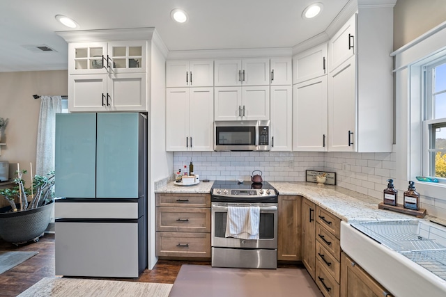 kitchen featuring decorative backsplash, light stone countertops, stainless steel appliances, dark wood-type flooring, and white cabinets