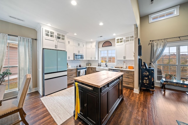 kitchen with dark hardwood / wood-style flooring, white cabinetry, stainless steel appliances, and a wealth of natural light