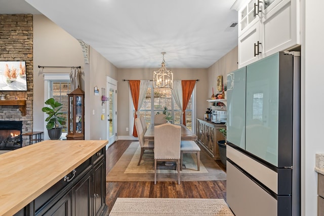 dining room with dark hardwood / wood-style floors, a fireplace, and an inviting chandelier