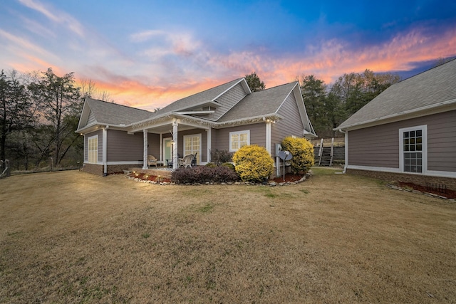 property exterior at dusk featuring a yard and a porch