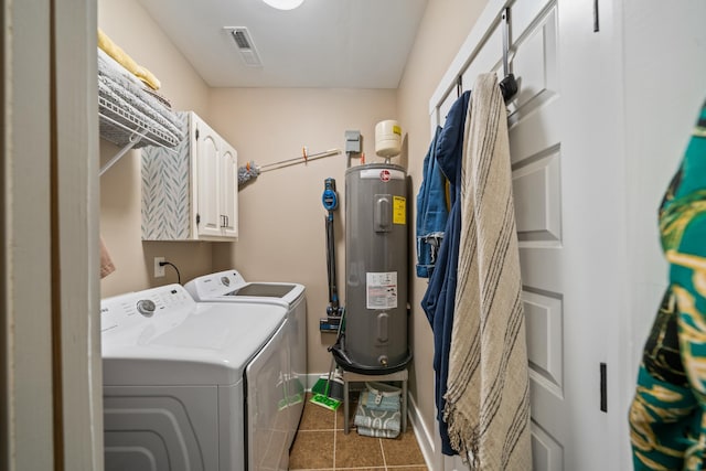 clothes washing area featuring cabinets, dark tile patterned flooring, washer and clothes dryer, and water heater