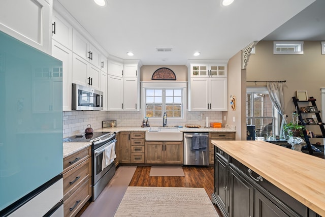 kitchen featuring white cabinets, a wealth of natural light, light stone countertops, and appliances with stainless steel finishes