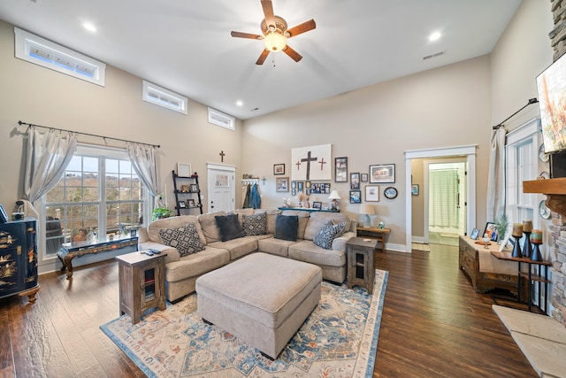 living room with a high ceiling, dark hardwood / wood-style flooring, and ceiling fan