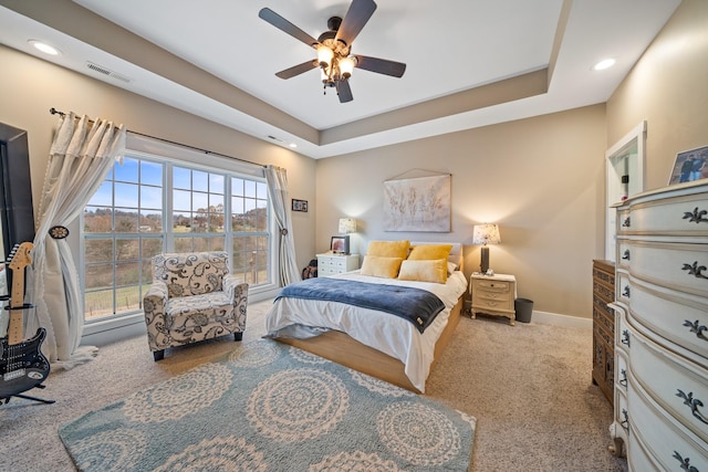 bedroom with a raised ceiling, ceiling fan, and light colored carpet