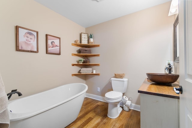 bathroom featuring toilet, hardwood / wood-style floors, vanity, and a washtub