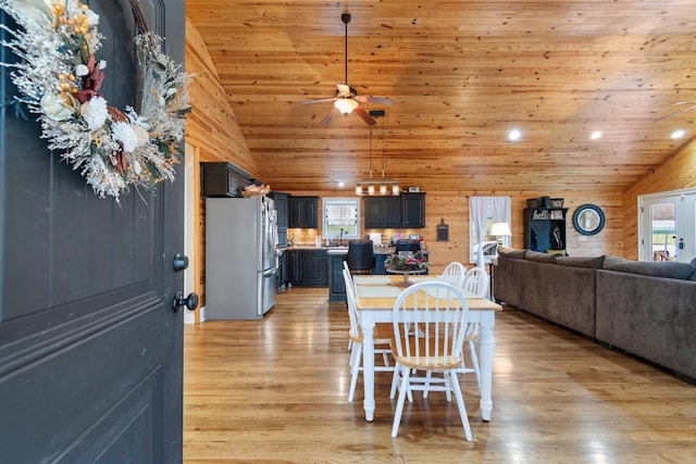 dining area with sink, high vaulted ceiling, wooden ceiling, light hardwood / wood-style floors, and wood walls