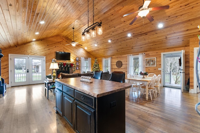 kitchen with wood-type flooring, wooden ceiling, a kitchen island, and wooden walls