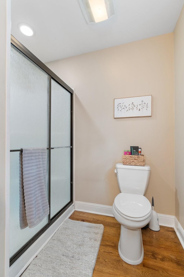 bathroom with hardwood / wood-style flooring, toilet, and walk in shower