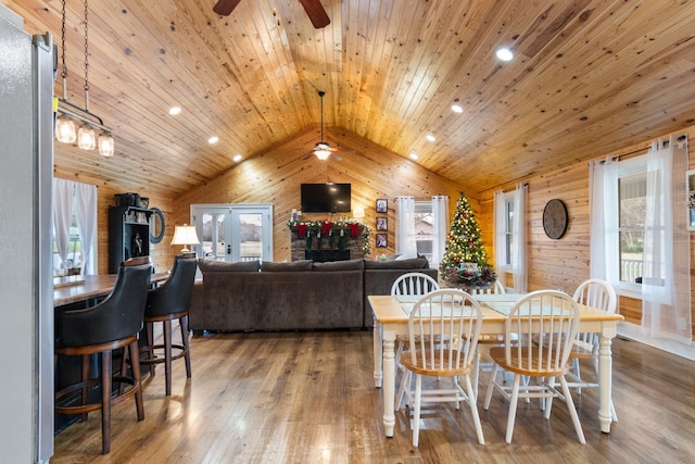 dining space with wooden walls, hardwood / wood-style floors, wood ceiling, and lofted ceiling