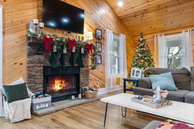 living room featuring a stone fireplace, wooden walls, wood-type flooring, and lofted ceiling