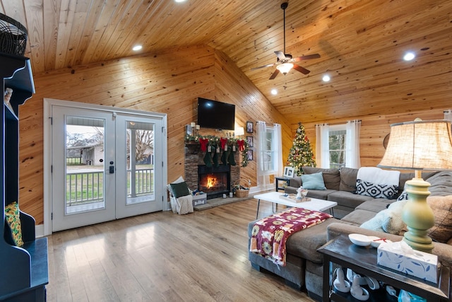 living room featuring french doors, light wood-type flooring, wood ceiling, ceiling fan, and wooden walls