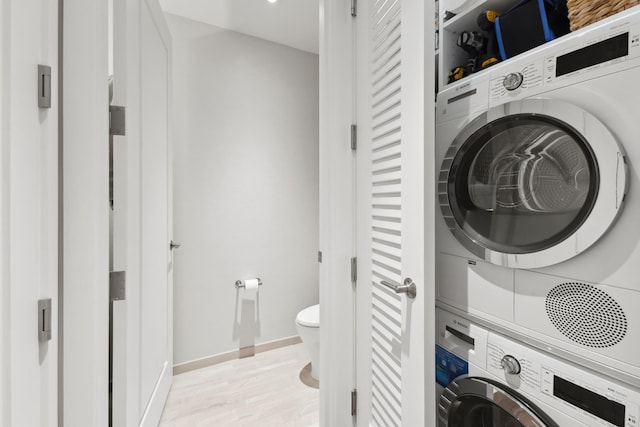 clothes washing area featuring light hardwood / wood-style floors and stacked washer / dryer