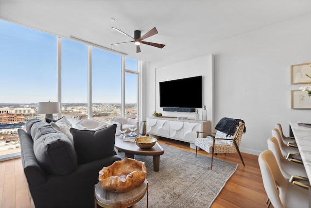 living room with ceiling fan, a wall of windows, and wood-type flooring