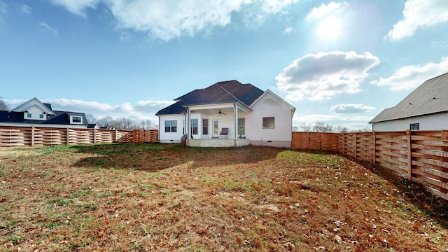 rear view of property featuring a yard and ceiling fan