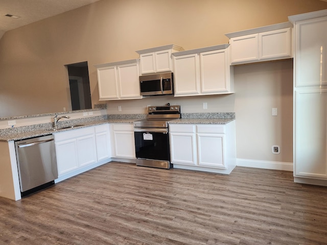 kitchen with light stone counters, white cabinetry, and stainless steel appliances