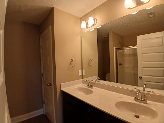 bathroom featuring vanity, a textured ceiling, and an enclosed shower