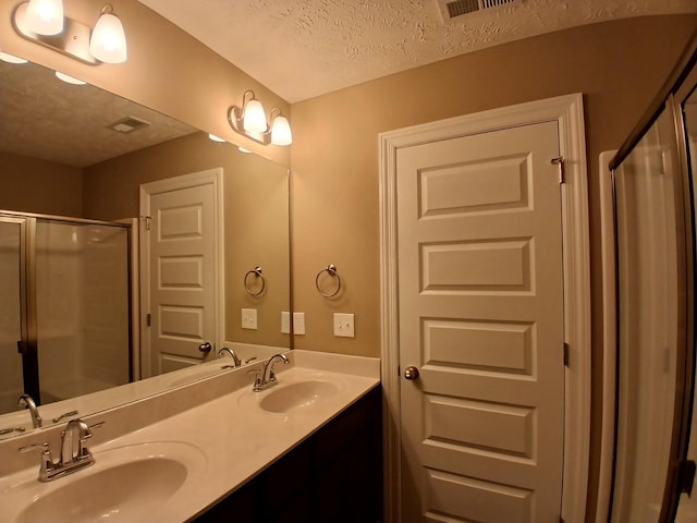 bathroom featuring walk in shower, vanity, and a textured ceiling