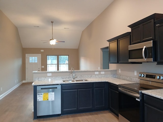 kitchen featuring ceiling fan, stainless steel appliances, light stone countertops, vaulted ceiling, and sink