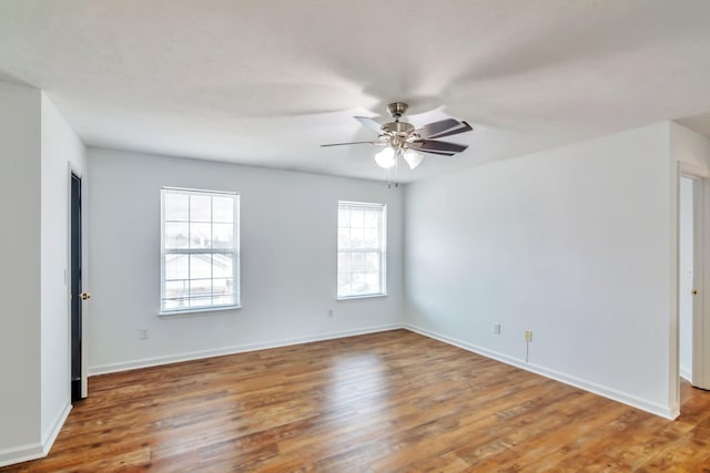 empty room featuring ceiling fan, a healthy amount of sunlight, and hardwood / wood-style flooring