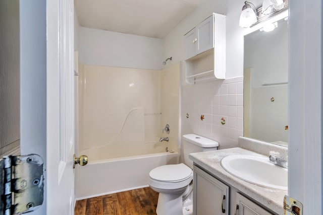 full bathroom with bathing tub / shower combination, hardwood / wood-style floors, toilet, vanity, and tile walls