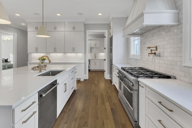 kitchen featuring custom range hood, stainless steel appliances, sink, white cabinets, and hanging light fixtures