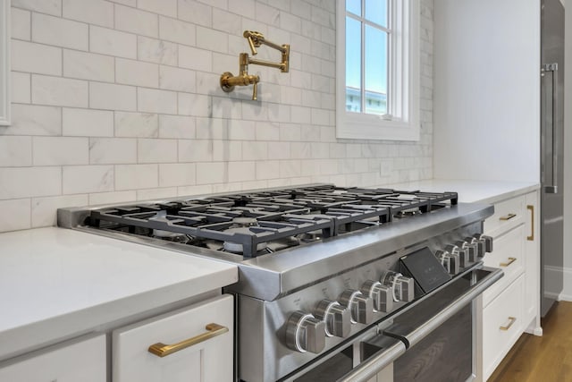 room details featuring decorative backsplash, high end stainless steel range, white cabinets, and dark wood-type flooring