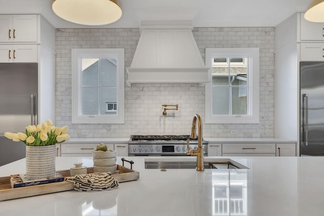 kitchen featuring premium range hood, sink, appliances with stainless steel finishes, tasteful backsplash, and white cabinetry