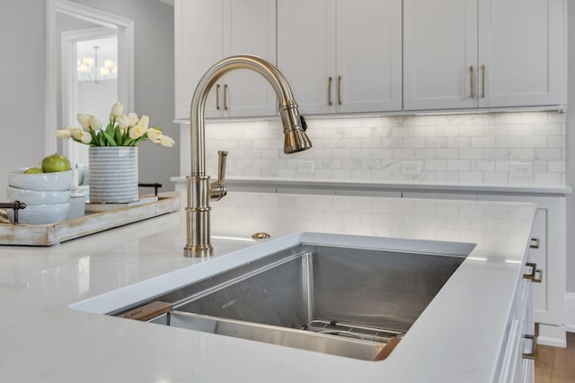 room details with backsplash, white cabinets, and sink