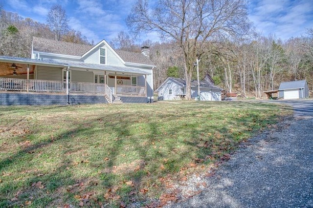 view of side of home with an outdoor structure, a porch, and a yard