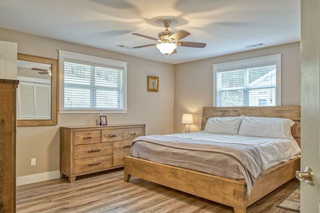 bedroom with multiple windows, light hardwood / wood-style floors, and ceiling fan